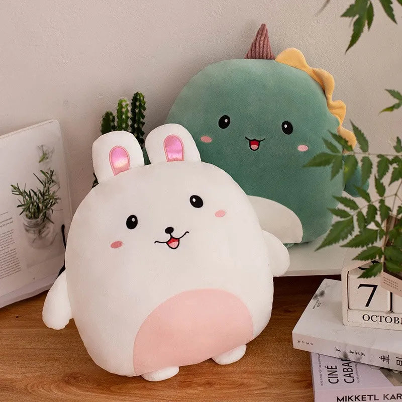 Two cute kawaii plush toys, one white with pink accents and the other green with a yellow bow, on a wooden surface with plants in the background.