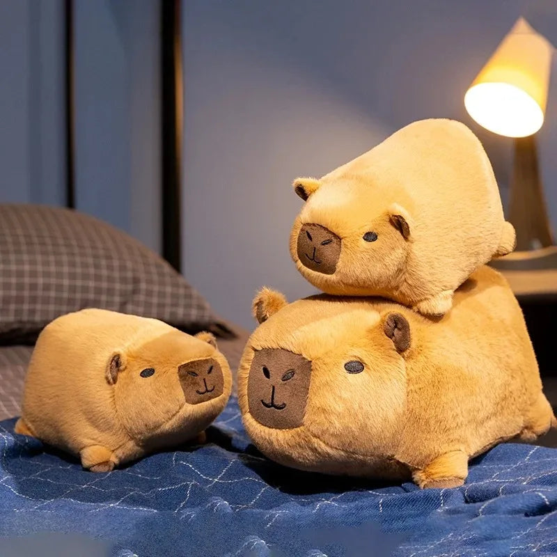 Three kawaii plush capybaras stacked on top of each other on a blue blanket.