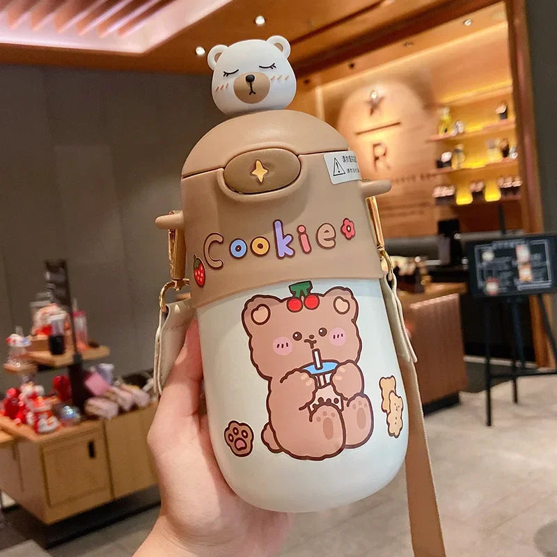 Cartoon bear-themed kawaii water bottle with 'Cookie' text held in a hand, blurred indoor background