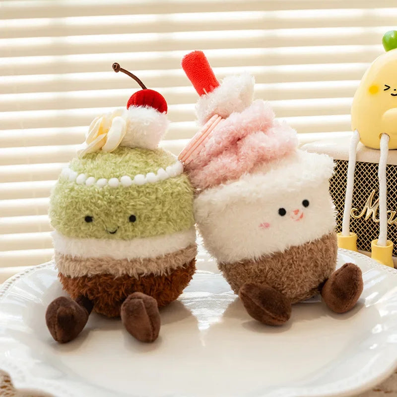 Two kawaii plush toys resembling cake slices with cherry and whipped cream on a white surface.