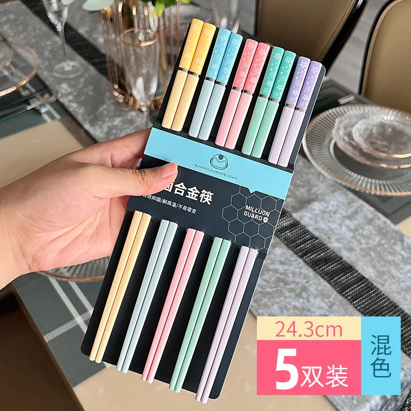 Pack of colorful kawaii chopsticks held by a hand with a dining table background