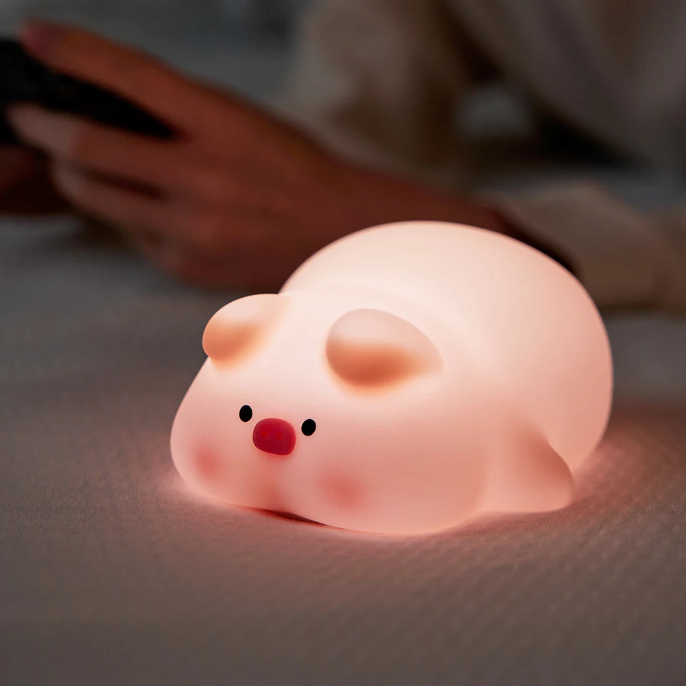 Pink pig-shaped kawaii night light on a soft surface with a blurred background