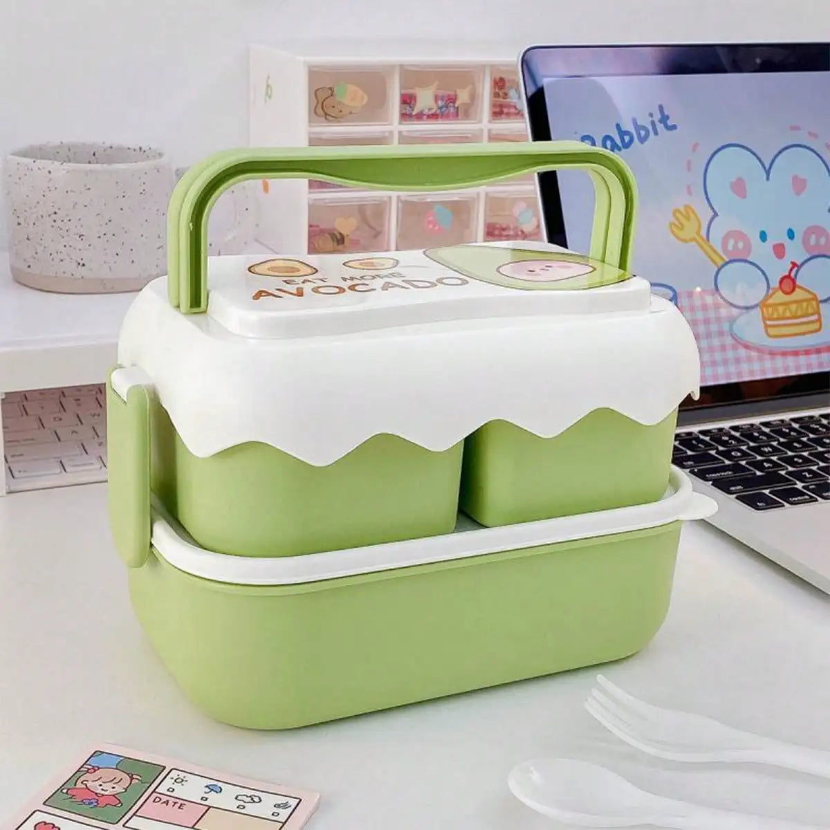 Green and white kawaii lunch box on a desk with a laptop in the background
