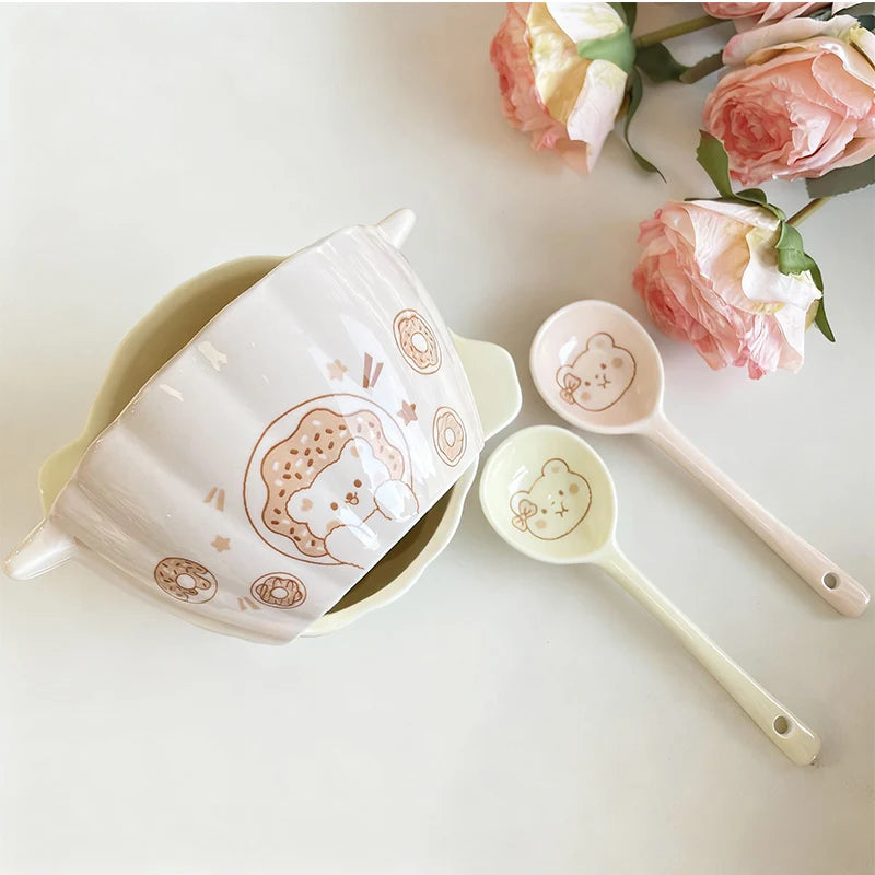 A pink pumpkin shaped kawaii bowl next to spoons
