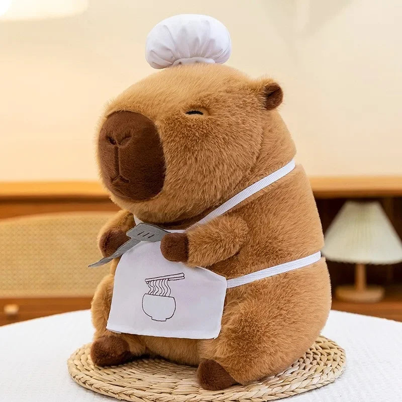 Kawaii plush bear toy wearing a chef's hat and apron with a kitchen towel, on a light background.