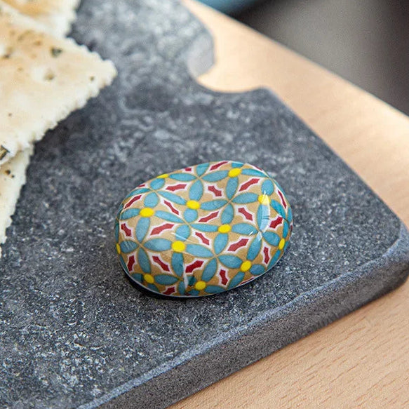 Colorful patterned kawaii chopstick holder on a dark slate surface with crackers