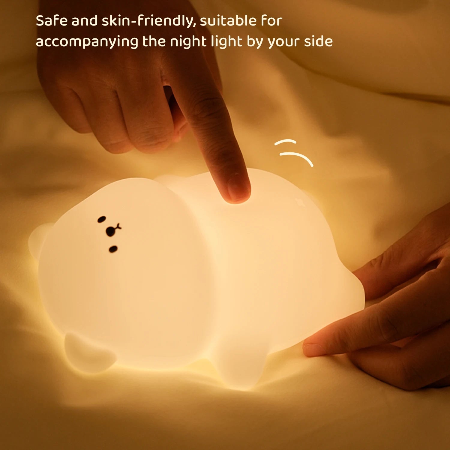 Person interacting with a soft, glowing kawaii night light shaped like a cartoon character on a bed.