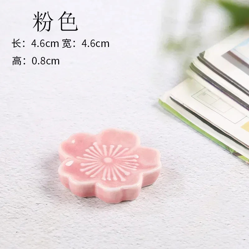 Pink flower-shaped kawaii chopstick holder on a textured surface with text indicating dimensions.