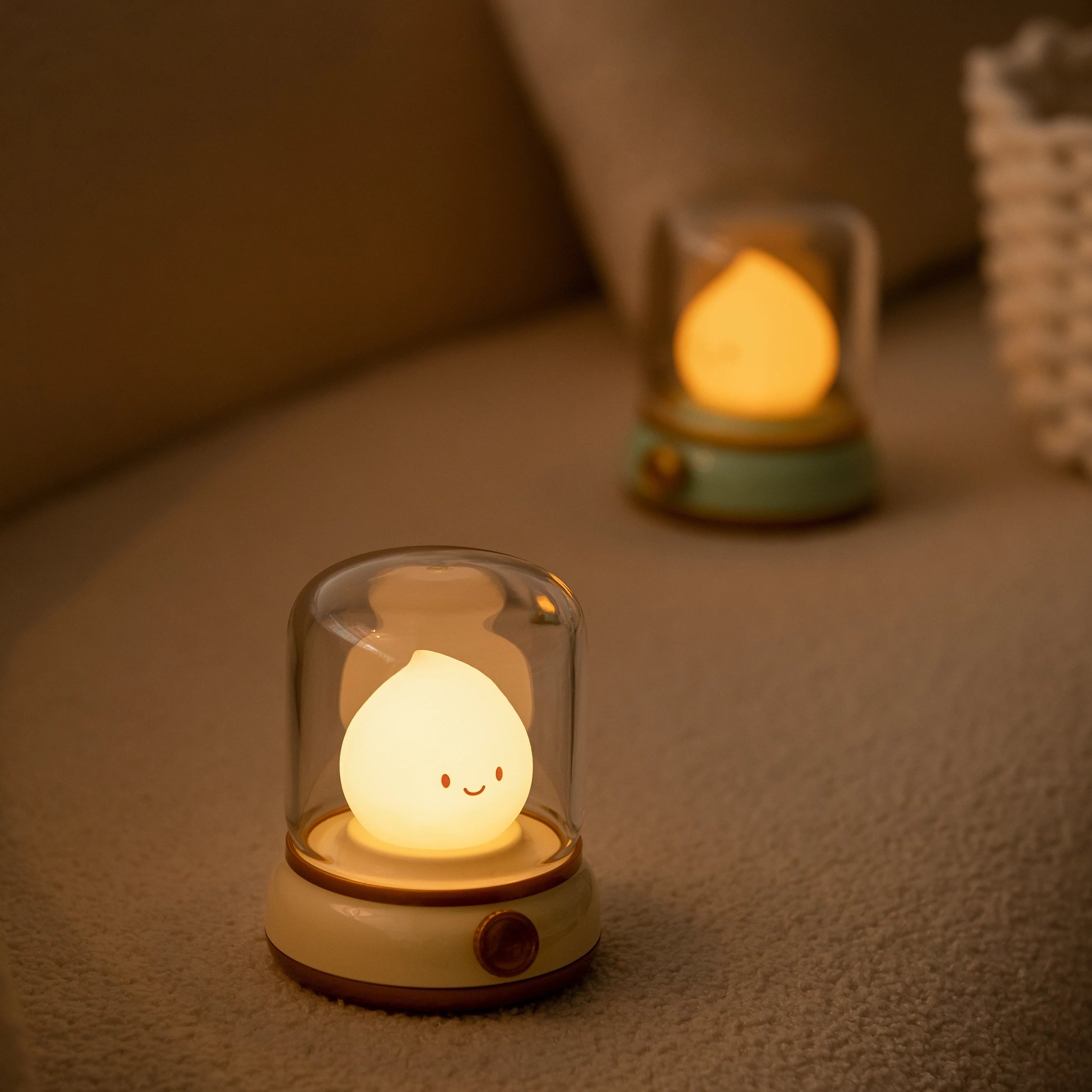 Two small night lights with kawaii smiling faces on a soft surface.