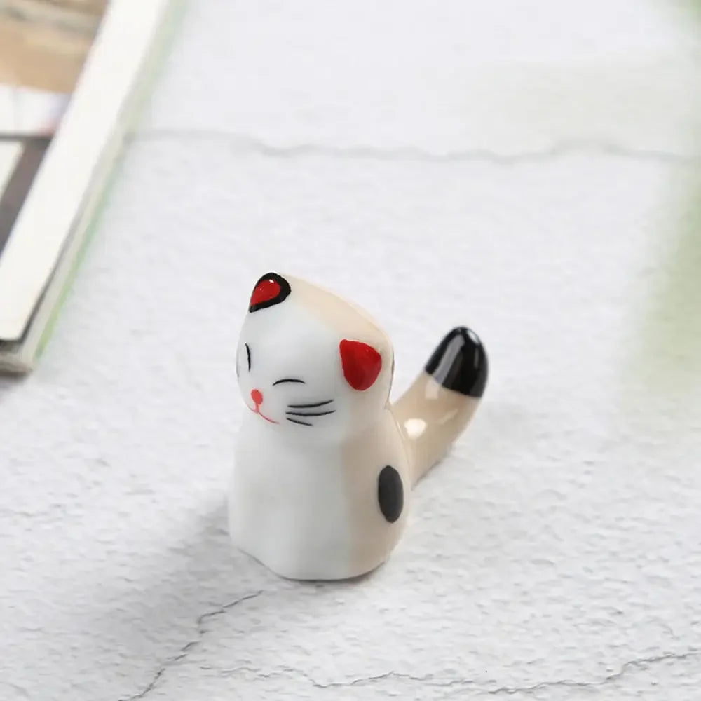 Small ceramic kawaii cat figurine with red accents on a light surface