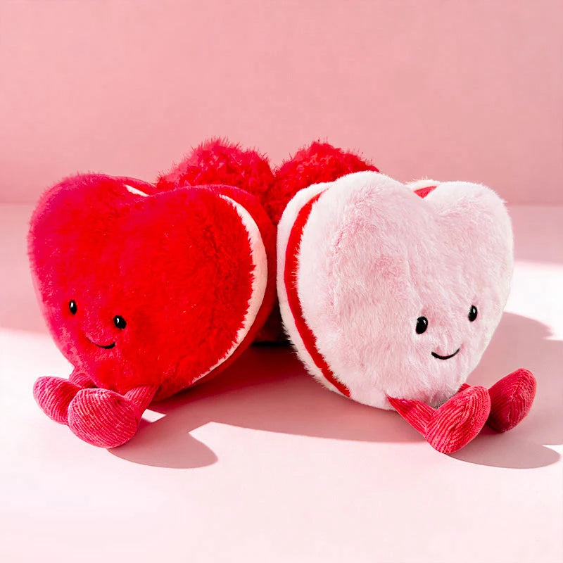 Two kawaii plush heart-shaped toys, one red and one white, on a pink background.
