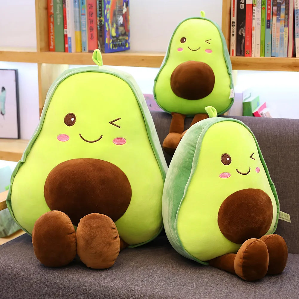 Three kawaii plush avocado toys on a couch with a bookshelf in the background