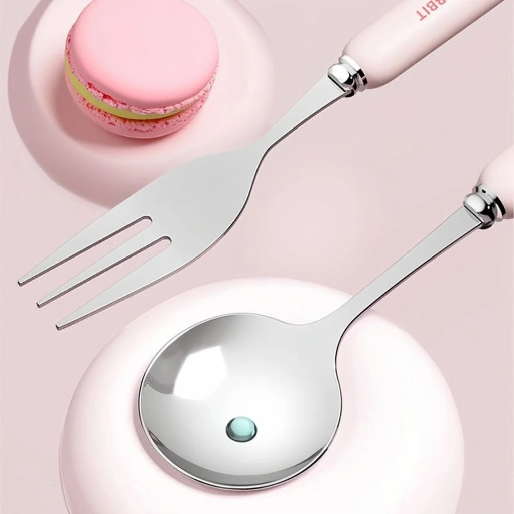 Silver kawaii utensils with pink handles on a pink background with a pink macaron.