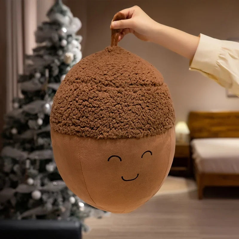 Kawaii plush acorn-shaped pillow with a face held by a hand in a room with a Christmas tree.