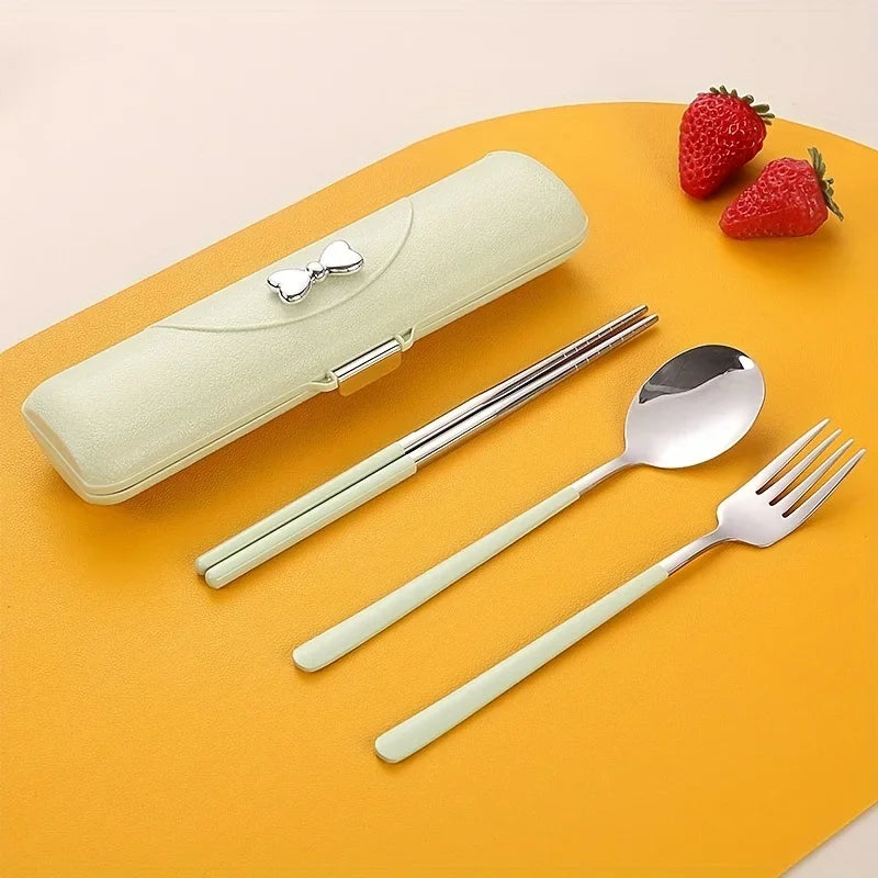 Set of silver kawaii utensils with a light green case on an orange surface with strawberries.