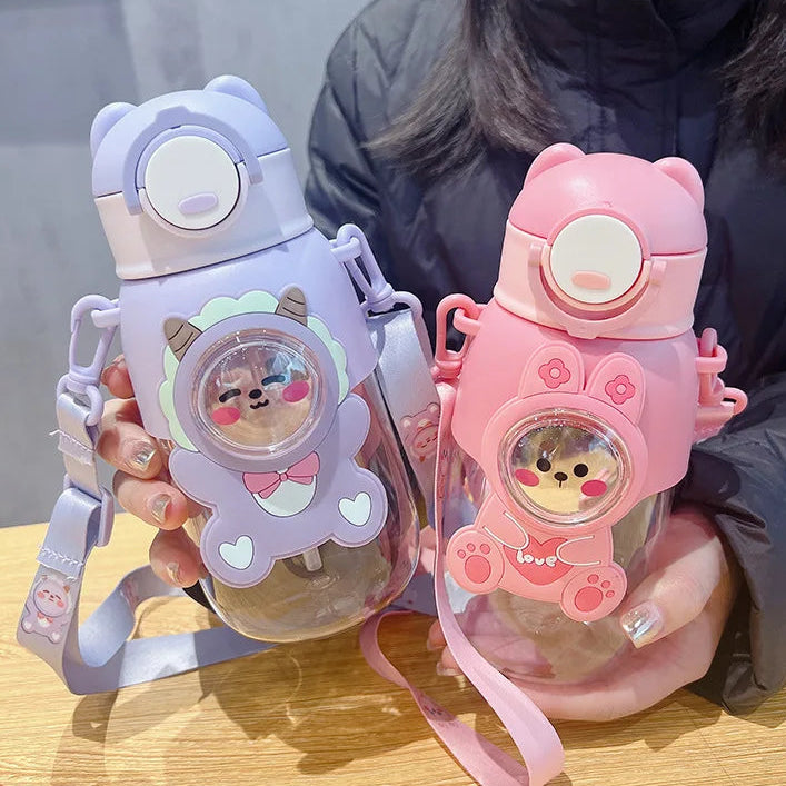 Two cartoon-themed kawaii water bottles, one purple and one pink, held by a person.