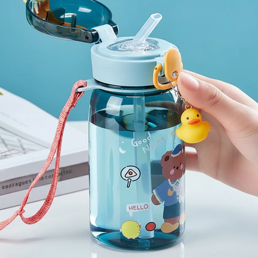 Children's kawaii water bottle with cartoon design and straw, held by a hand against a light blue background.