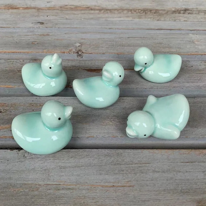 Five light blue ceramic duck kawaii chopstick holders on a wooden surface