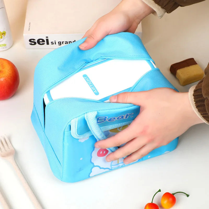 Blue kawaii lunch box with a hand reaching inside, surrounded by fruits and utensils on a table.