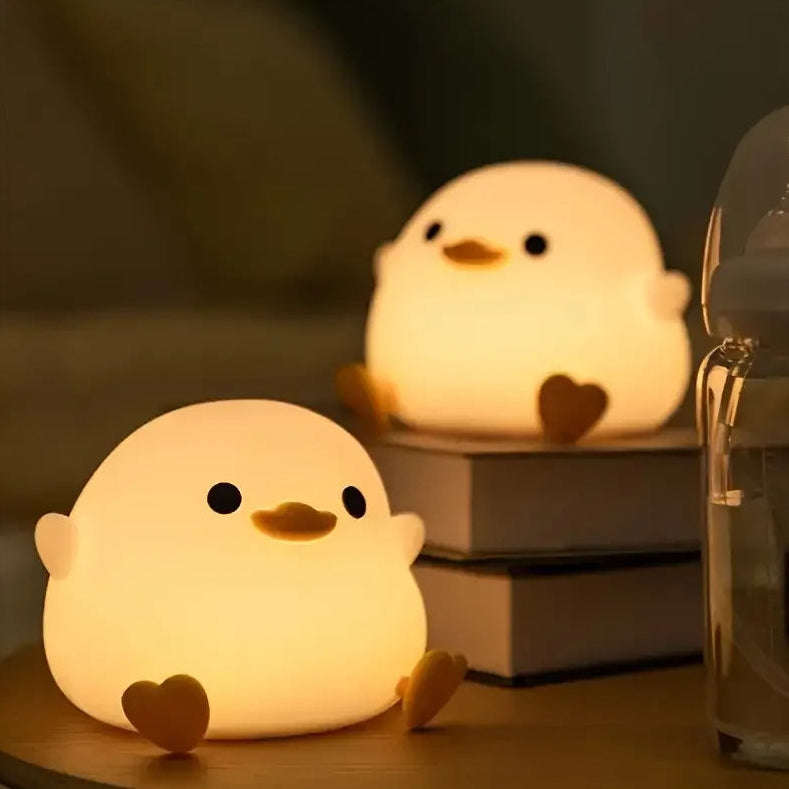 Two cute chick-shaped kawaii night lights on a table with a blurred background