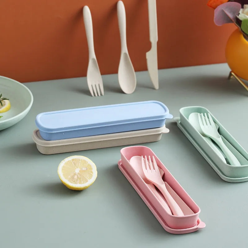 Set of colorful kawaii utensils in carrying cases on a table with a lemon and a plant.