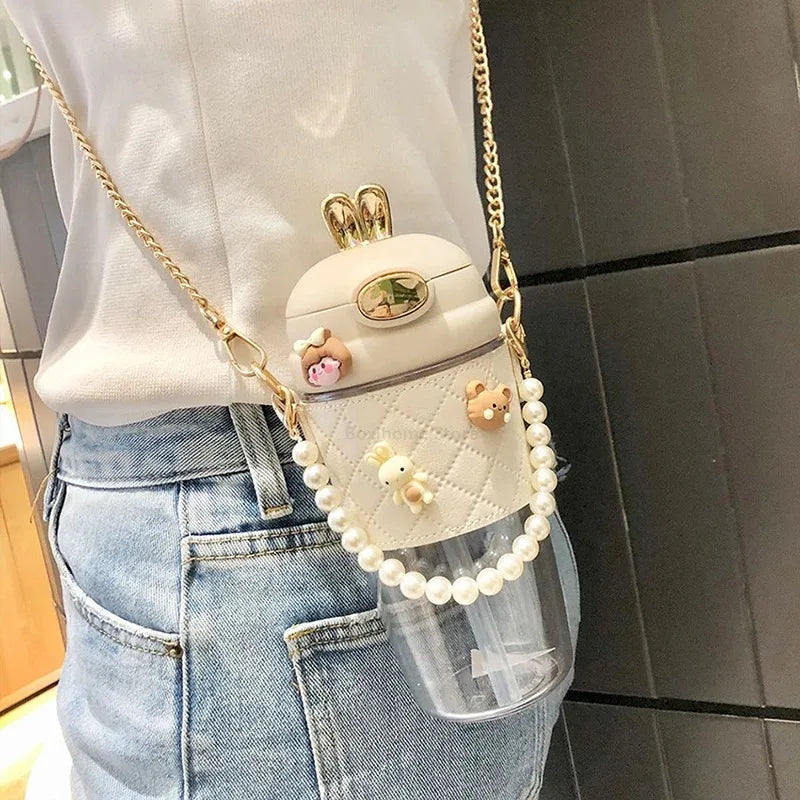 White kawaii water bottle with decorative elements and chain strap worn by a person.