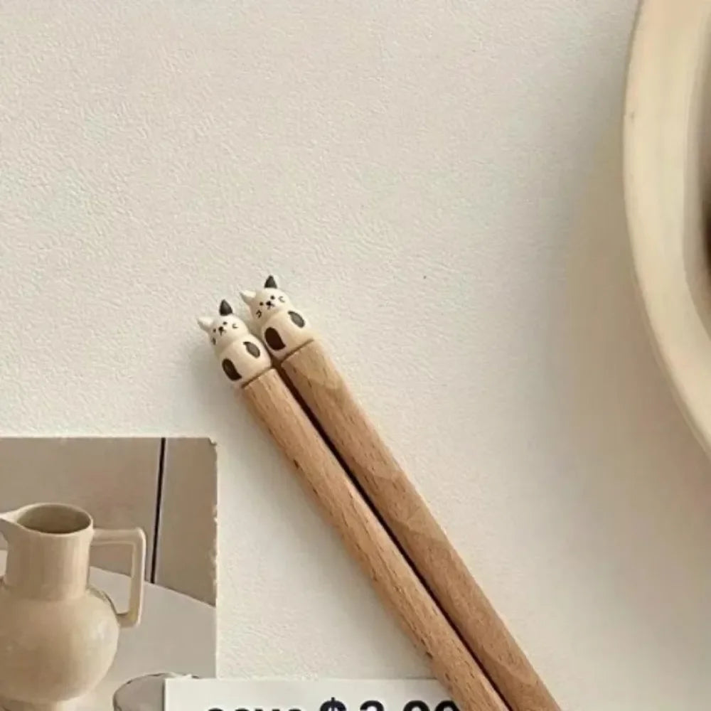 Wooden kawaii chopsticks with cat-shaped ends on a light surface
