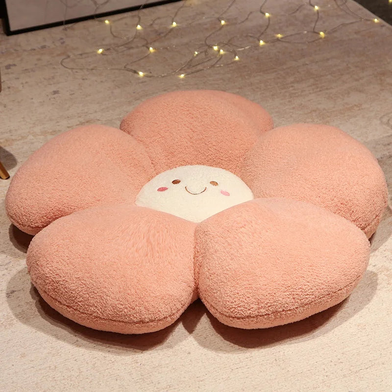 Flower-shaped pink kawaii cushion with a smiling face on a wooden floor.