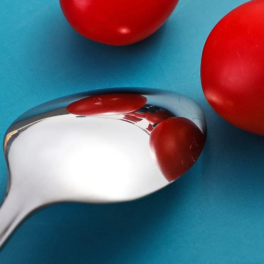 Kawaii utensils on a blue background with a silver spoon reflecting the tomato.