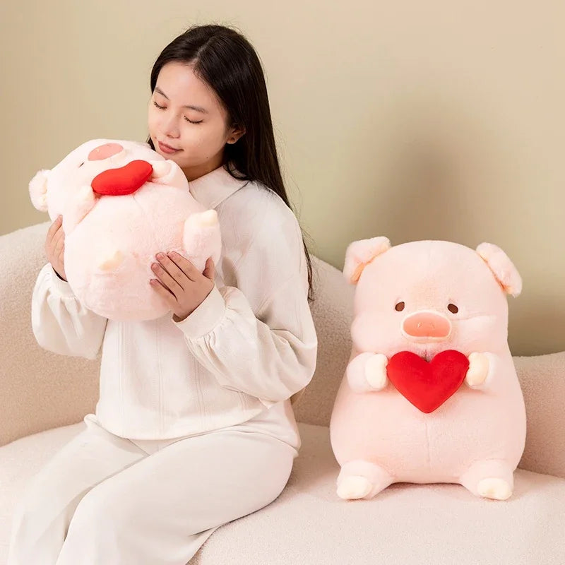 Woman holding a kawaii plush pig with a red heart, sitting on a couch next to another similar plush toy.