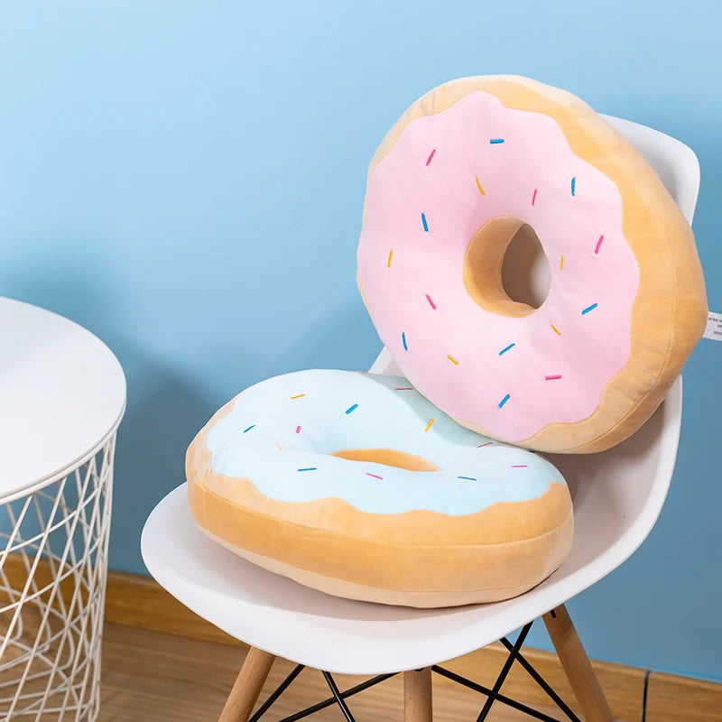 Donut-shaped kawaii cushions with pink icing and sprinkles on a white chair against a blue wall.