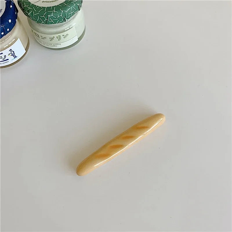 A bread shaped kawaii chopstick holder on a light gray surface with jars in the background