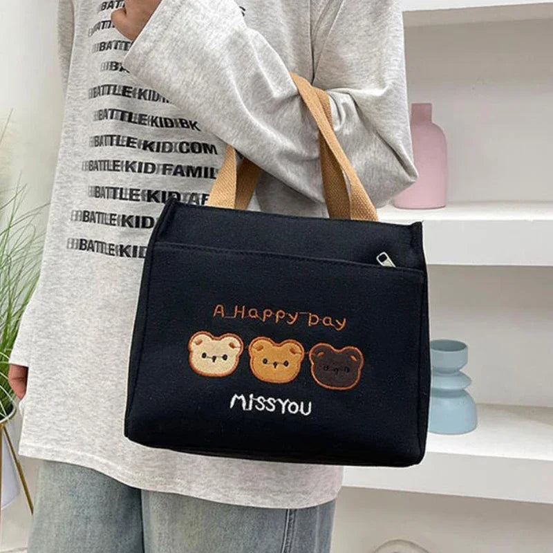 Person holding a black kawaii bag with bear illustrations and text in a home setting