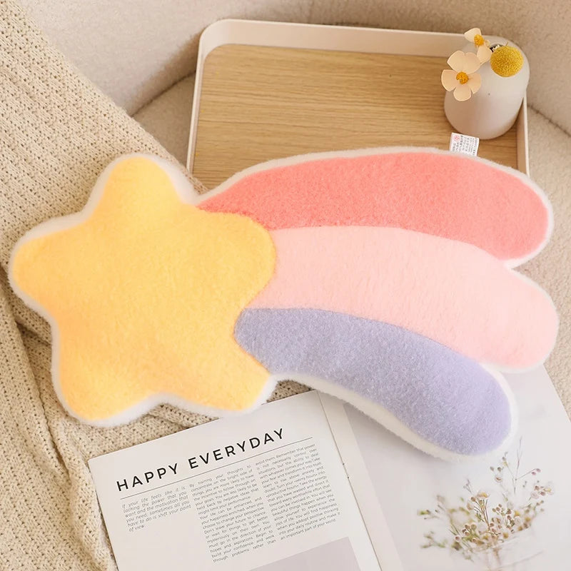 Colorful star-shaped kawaii cushion on a surface with a magazine and small plant.