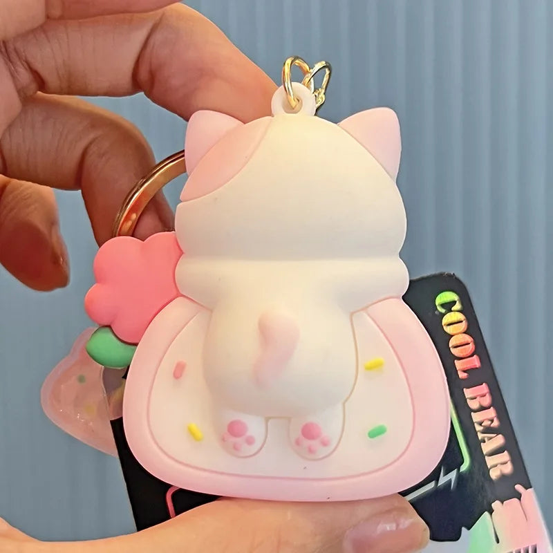Cute cartoon cat kawaii keychain held by a hand against a light blue background