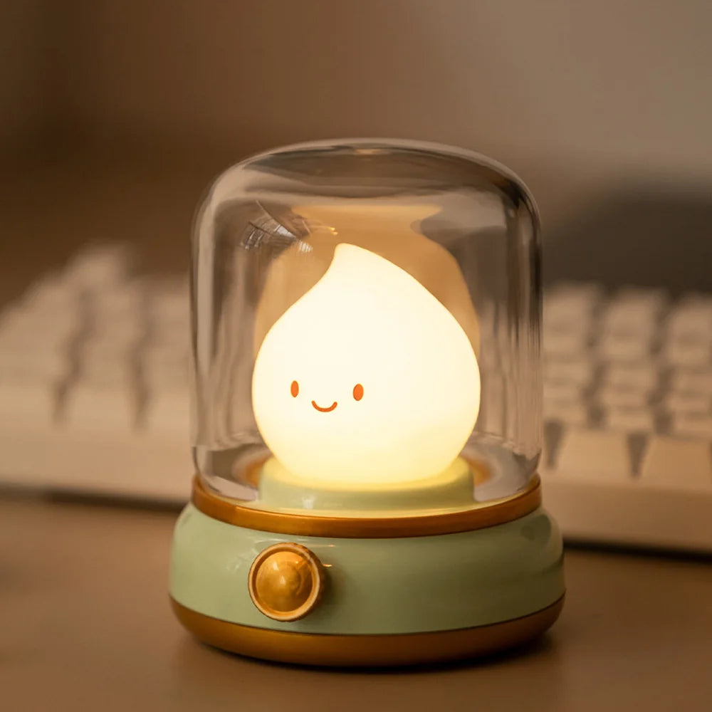 Cute kawaii lamp with a smiling face inside a glass dome on a desk with a keyboard in the background.