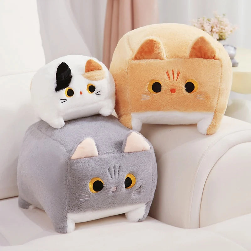 Three cat-shaped kawaii plush toys in white, orange, and gray on a light-colored couch.