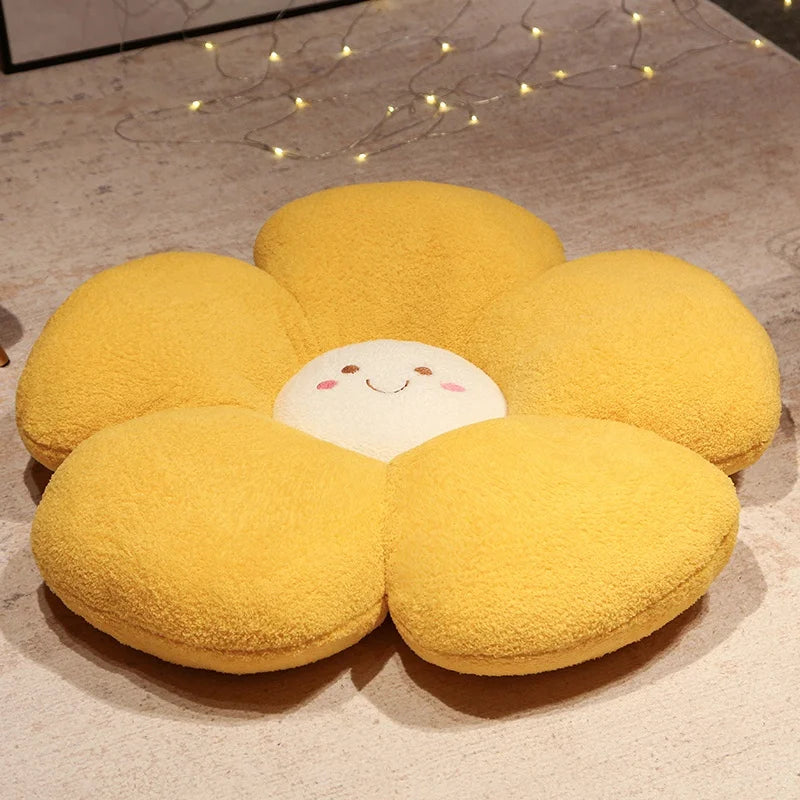 Yellow flower-shaped kawaii cushion with a smiling face on a wooden floor.
