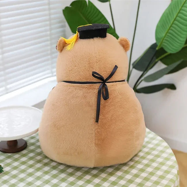 Kawaii plush toy resembling a bear with a black bow tie on a checkered tablecloth.