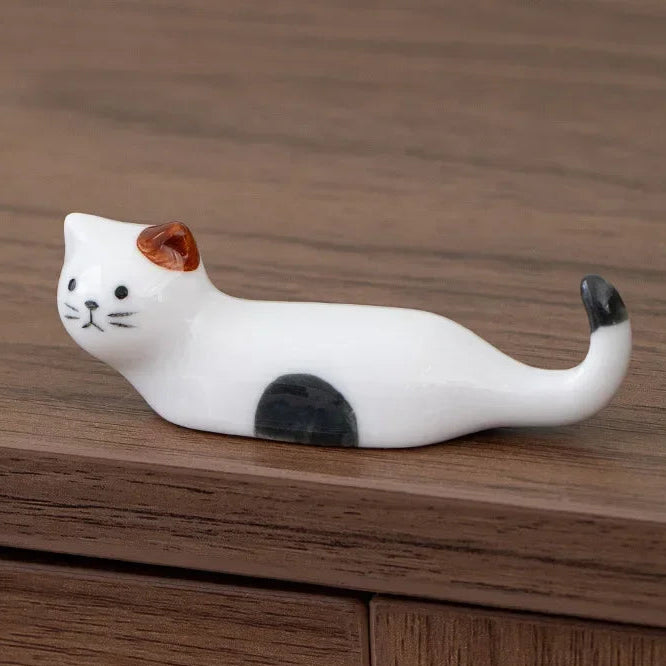Cat-shaped ceramic kawaii chopstick holders on a wooden surface with dimensions displayed.