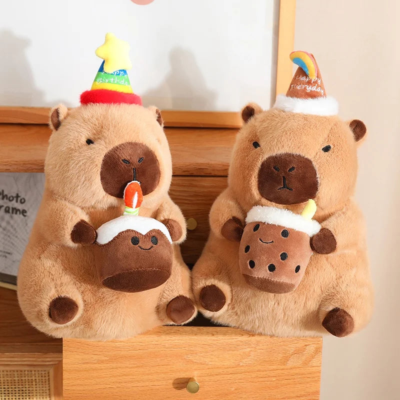 Two capybara plush toys with party hats and cake decorations on a wooden surface.