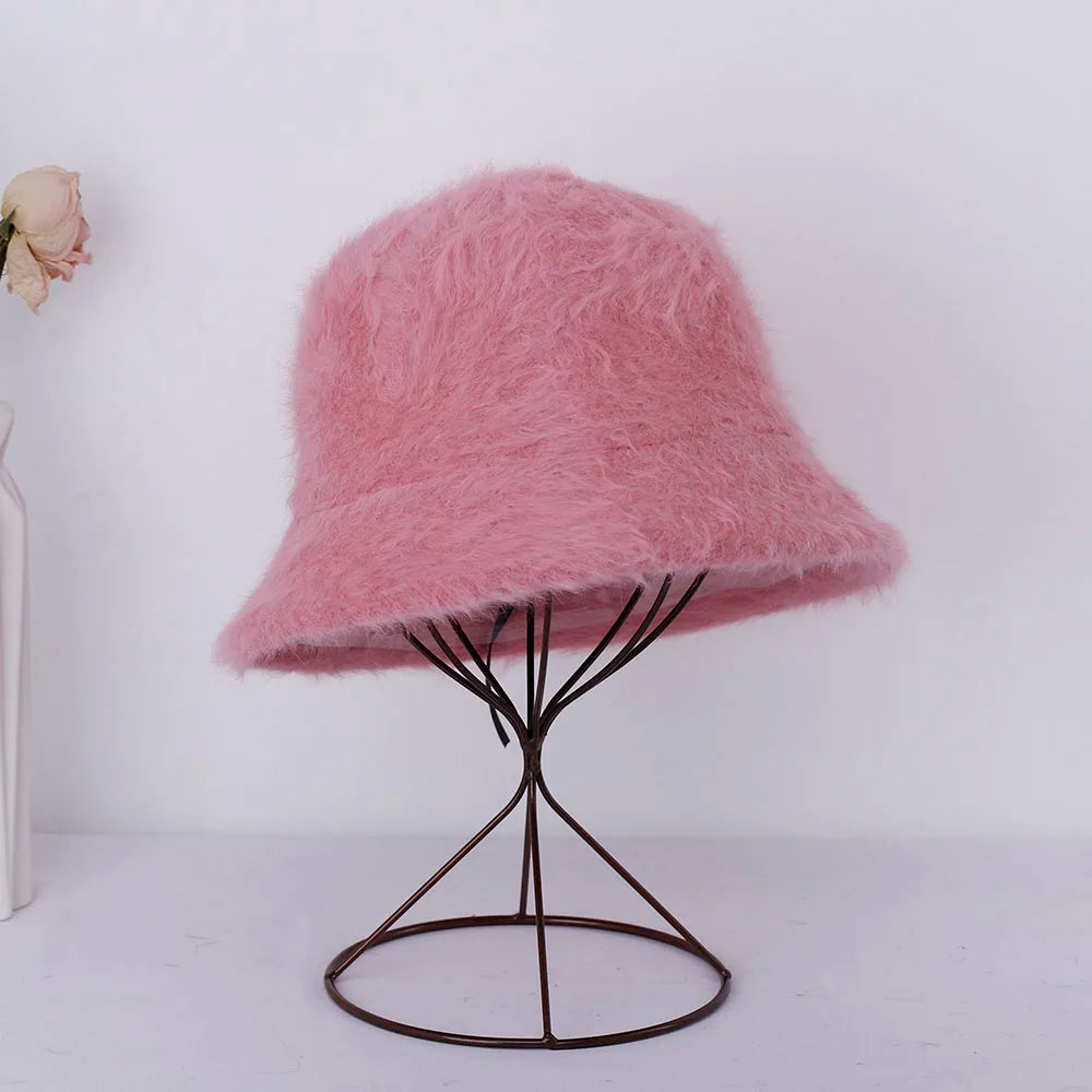 Pink fuzzy Kawaii hat on a black wire stand against a white background