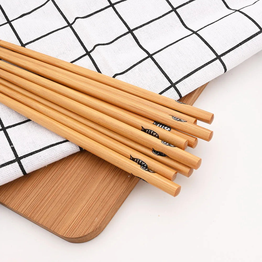 Bamboo kawaii chopsticks on a wooden cutting board with a checkered cloth background