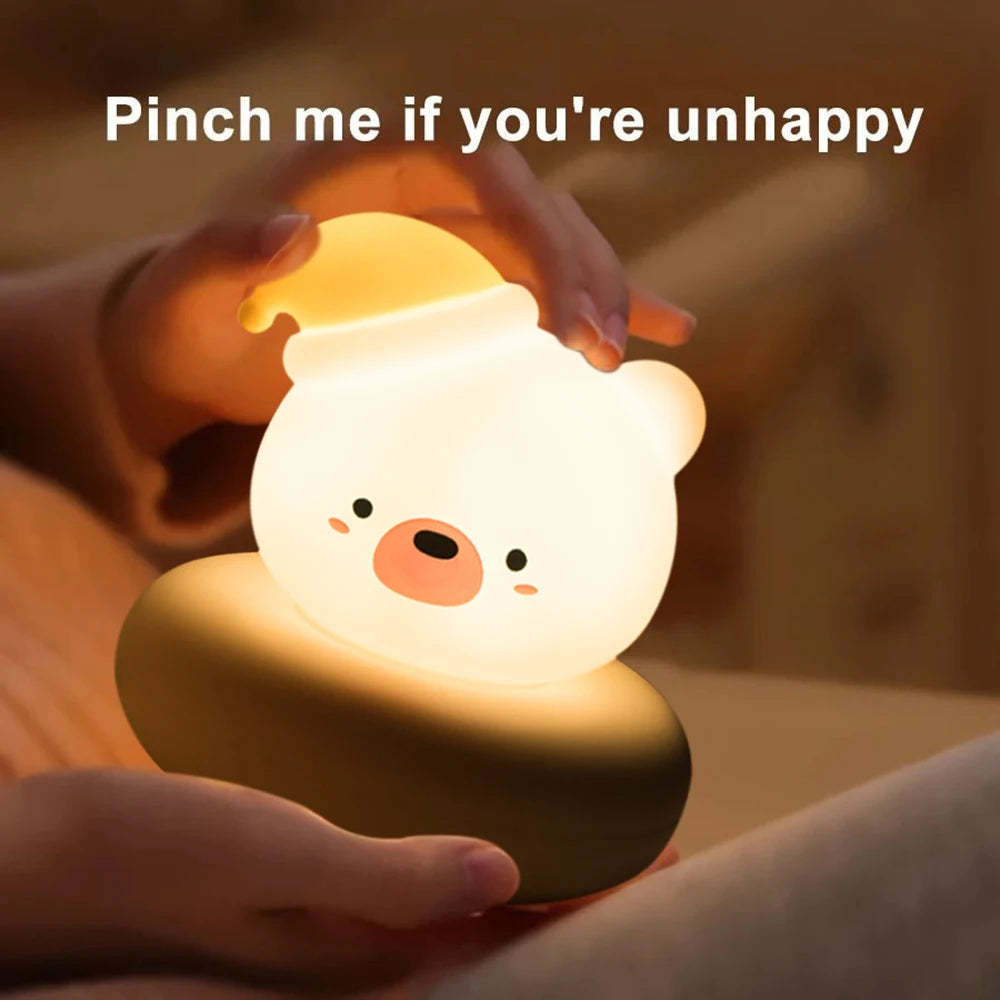 Cute kawaii animal-shaped night light held by a hand with text 'Pinch me if you're unhappy' on a blurred background.