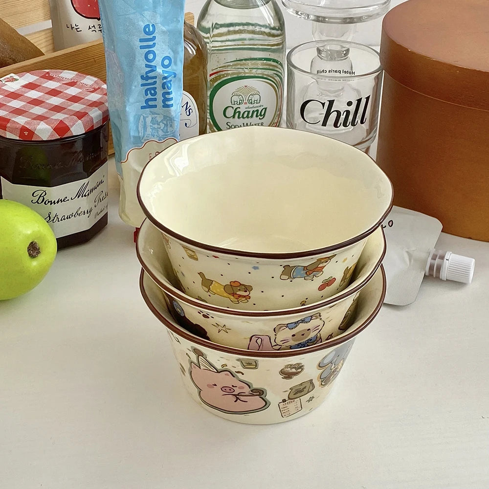 Stack of ceramic kawaii ramen bowls with animal illustrations on a table with various items including a bottle and a jar.