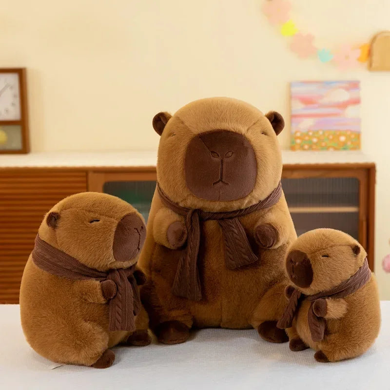 Three brown kawaii teddy bears with scarves on a white surface, with a blurred indoor background.