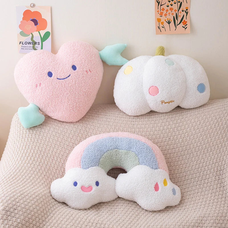 Three kawaii plush toys shaped like a heart, cloud, and rainbow on a textured surface with floral decorations in the background.