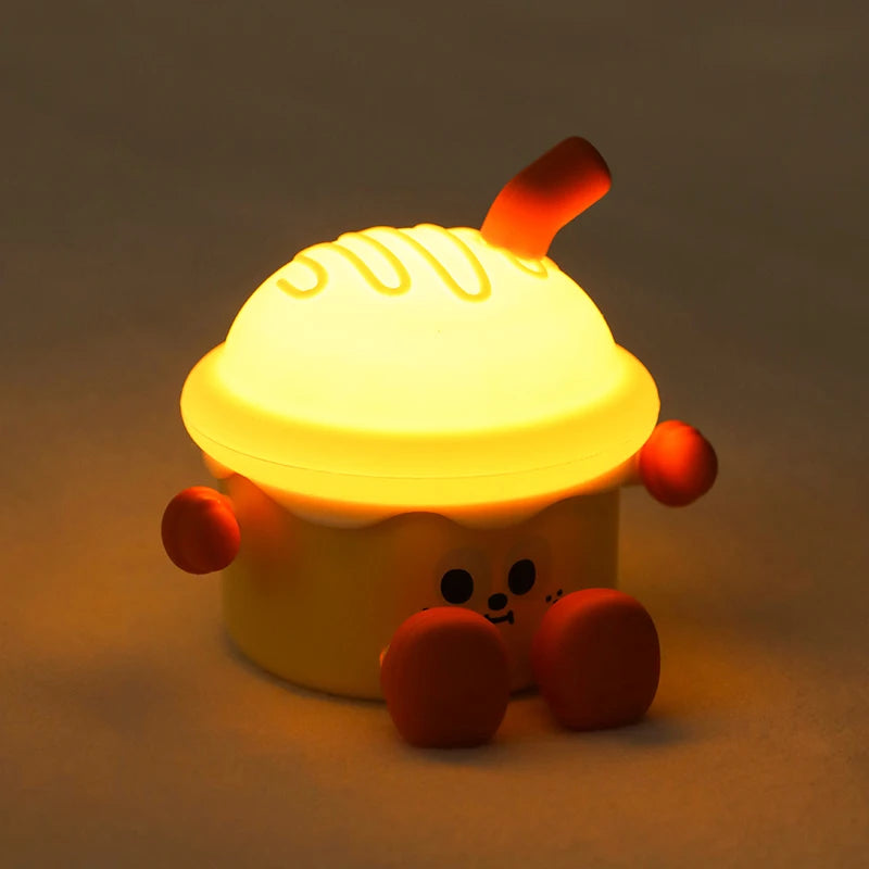 Cute, cartoonish dessert-shaped kawaii night light with a warm glow on a dark background