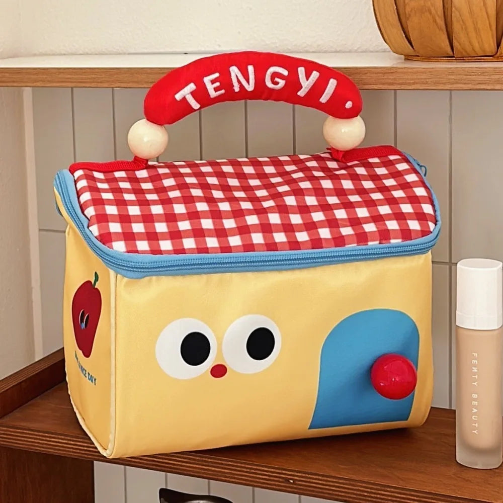 Children's kawaii lunch bag with a checkered red lid and cartoon face design on a wooden surface.