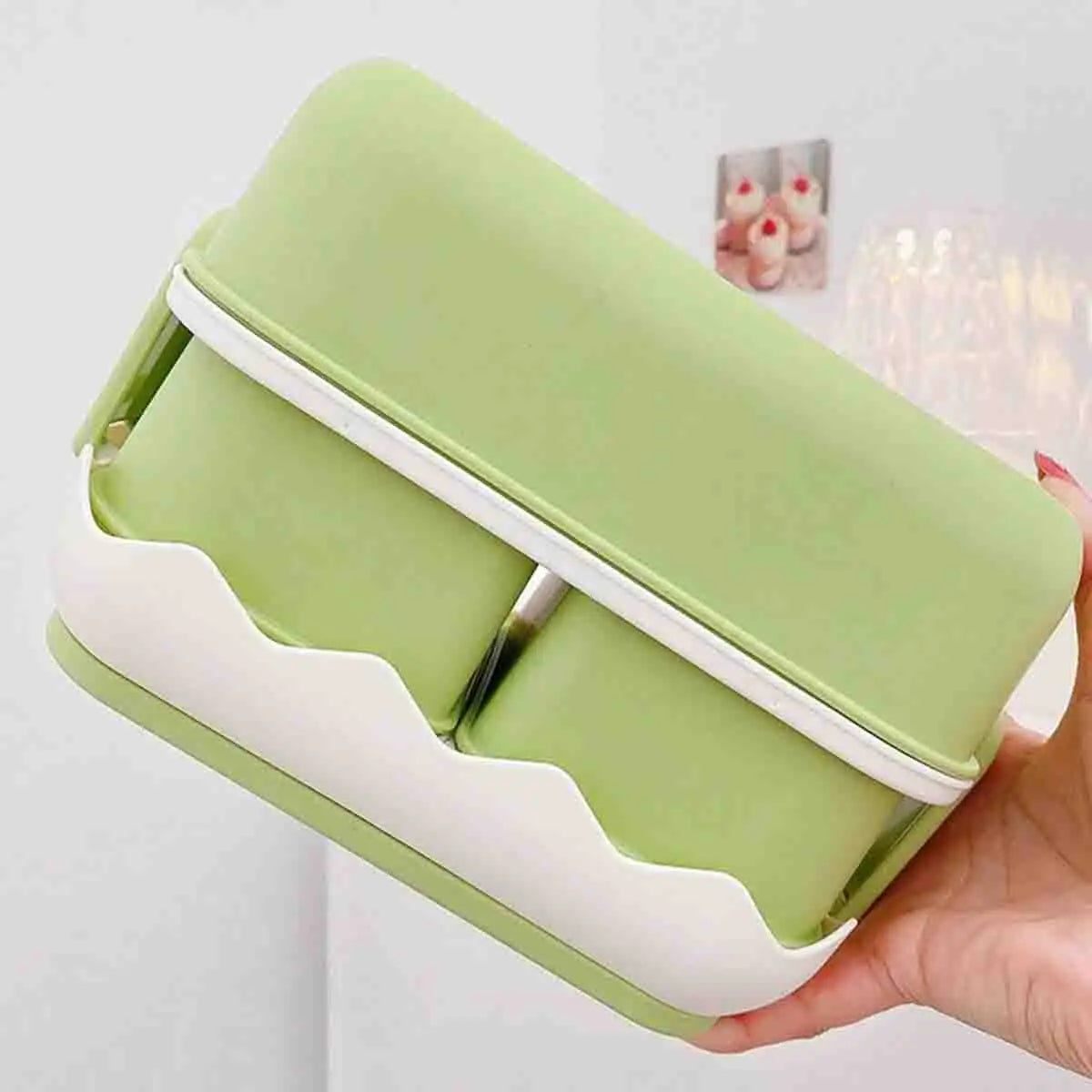Green and white kawaii food container held by a hand against a light background